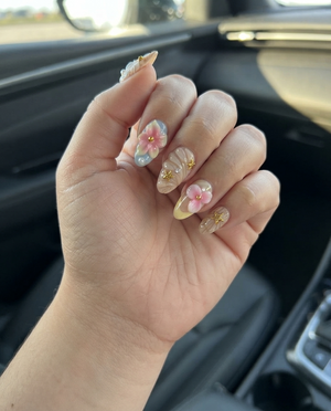 A set of pink press-on nails featuring 3D flowers, starfish, seashells, pearls, and gold star details.