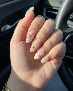 A set of pink press-on nails featuring 3D flowers, starfish, seashells, pearls, and gold star details.