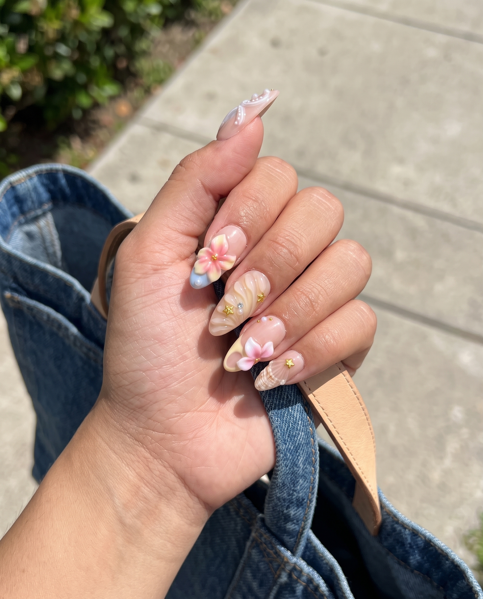 A set of pink press-on nails featuring 3D flowers, starfish, seashells, pearls, and gold star details.