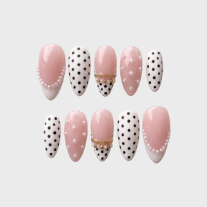 A set of Meevia Nails press-on nails featuring a mix of glossy pink bases, black polka dots on white, white pearl embellishments, and gold chain details.