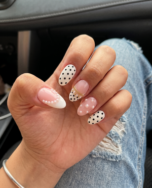 A set of Meevia Nails press-on nails featuring a mix of glossy pink bases, black polka dots on white, white pearl embellishments, and gold chain details.