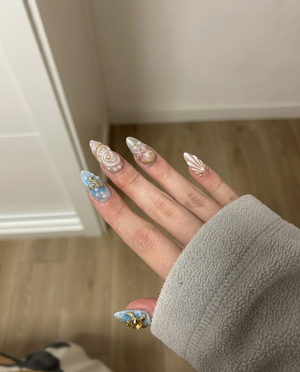 A set of stiletto press-on nails featuring ocean-themed designs with shells, pearls, starfish, and a sea turtle.