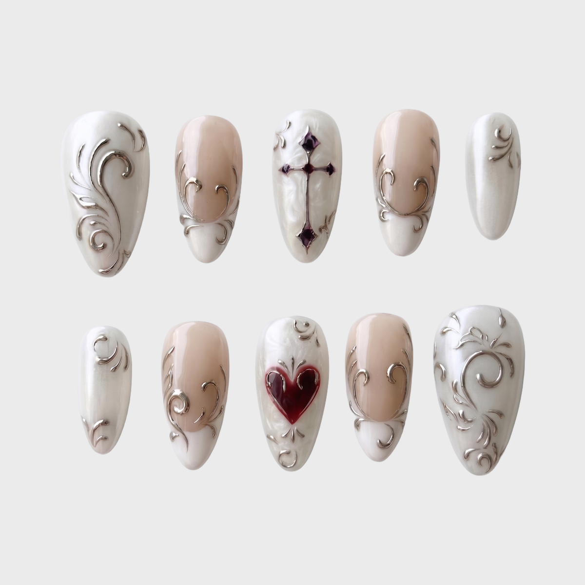 Pearl white press-on nails featuring metallic silver scrollwork, French tips, a dark red heart, and a gothic cross.