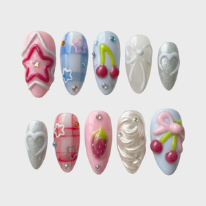A set of pastel pink and blue press-on nails featuring 3D cherries, strawberries, bows, stars, and silver glitter hearts.