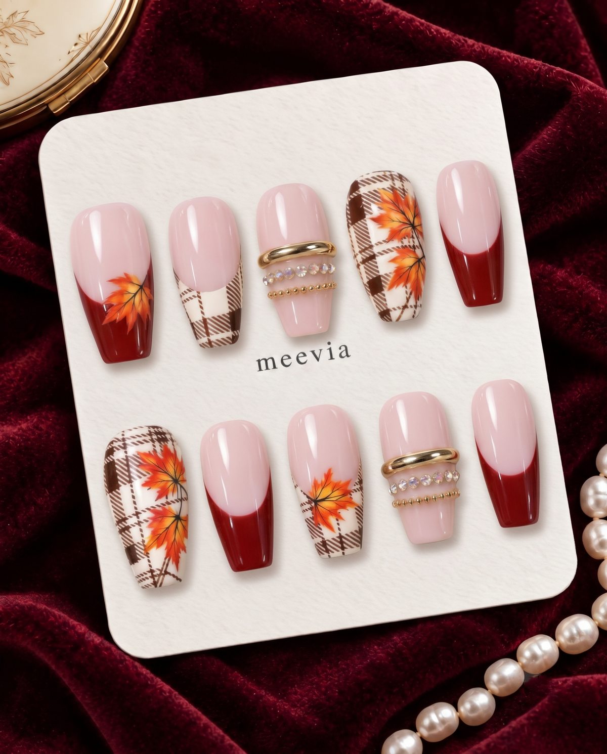 Pink and burgundy press-on nails with brown plaid, orange maple leaves, and gold accents