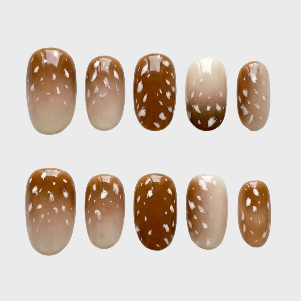 A set of brown ombre press-on nails with white fawn-inspired spots.