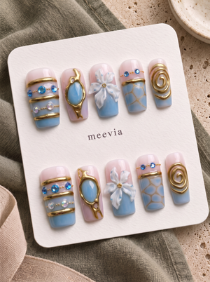 Blue and gold floral embellished press-on nails with glossy pink and blue details, gems, beads, and raised flower accents