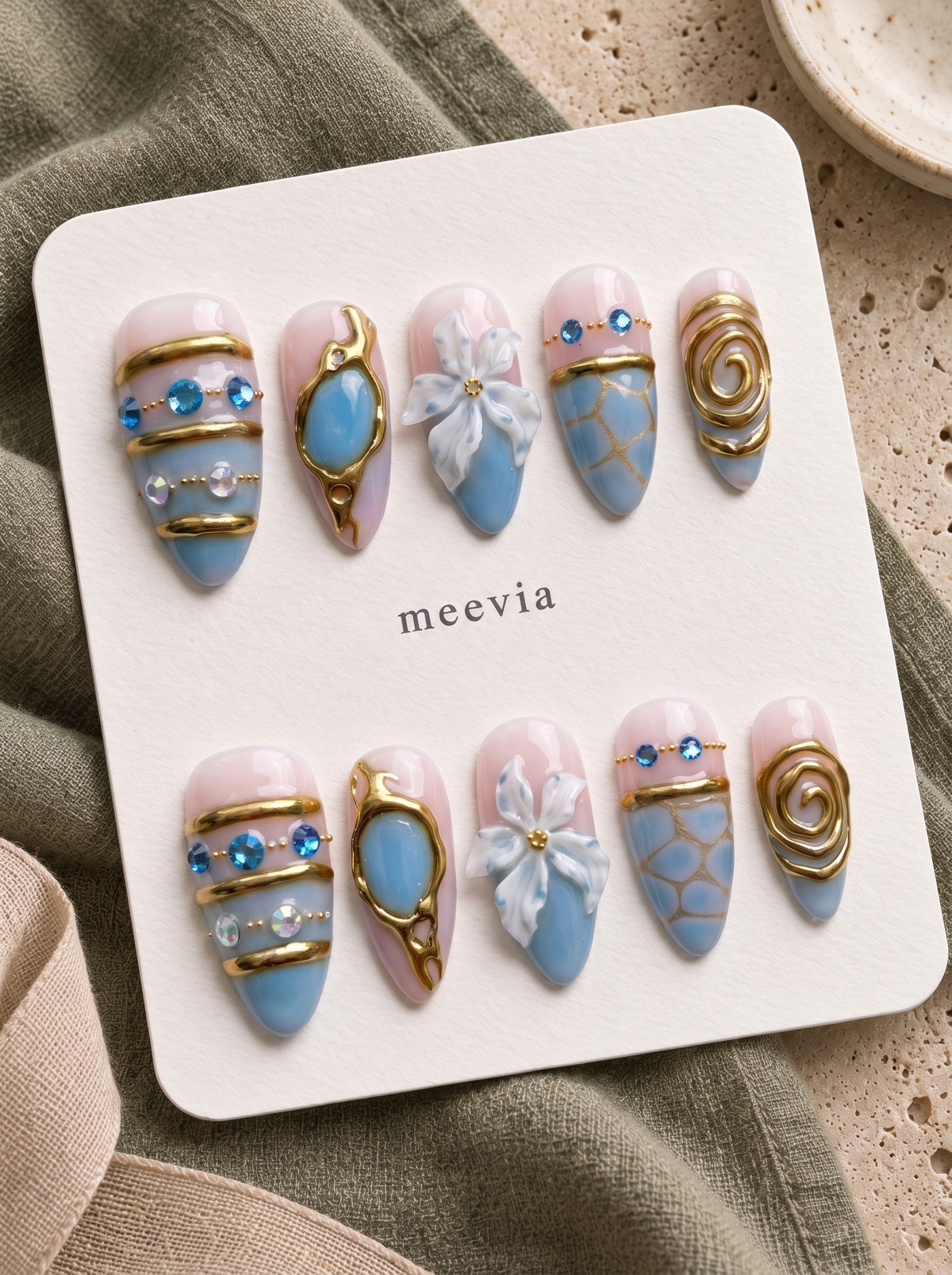 Blue and gold floral embellished press-on nails with glossy pink and blue details, gems, beads, and raised flower accents