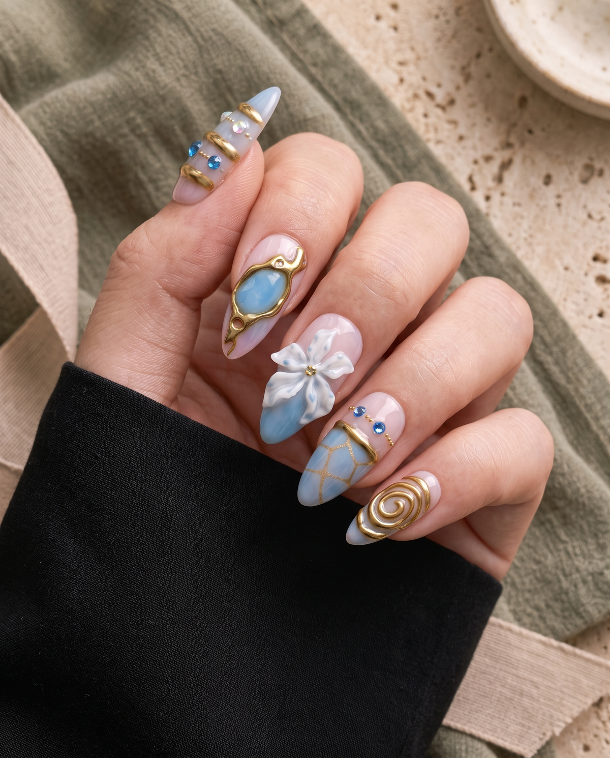 Blue and gold floral embellished press-on nails with glossy pink and blue details, gems, beads, and raised flower accents