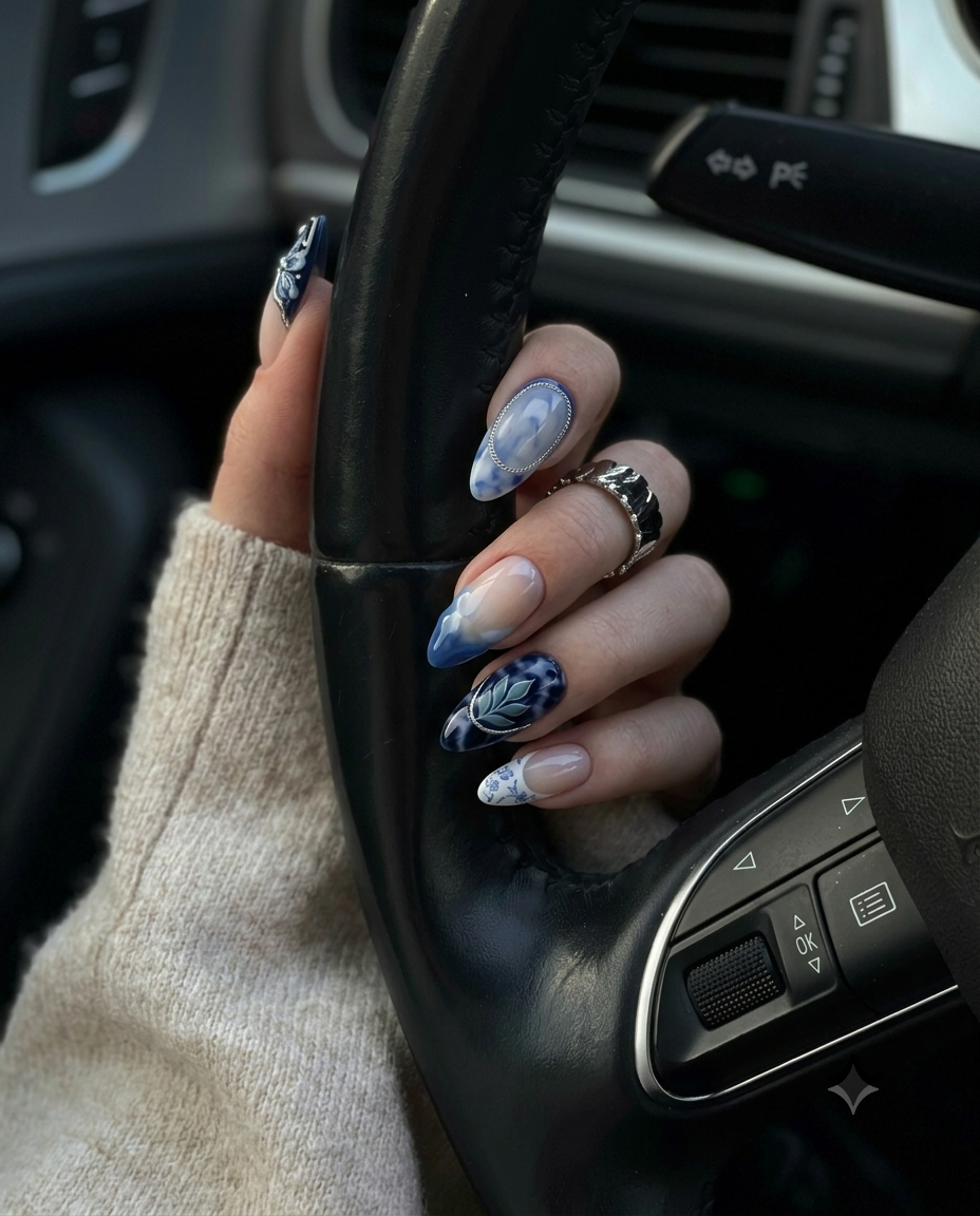 A set of blue and white porcelain-style press-on nails featuring floral patterns, marble designs, and silver accents.