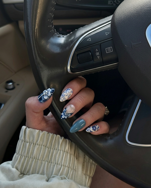 A set of blue and white porcelain-style press-on nails featuring floral patterns, marble designs, and silver accents.