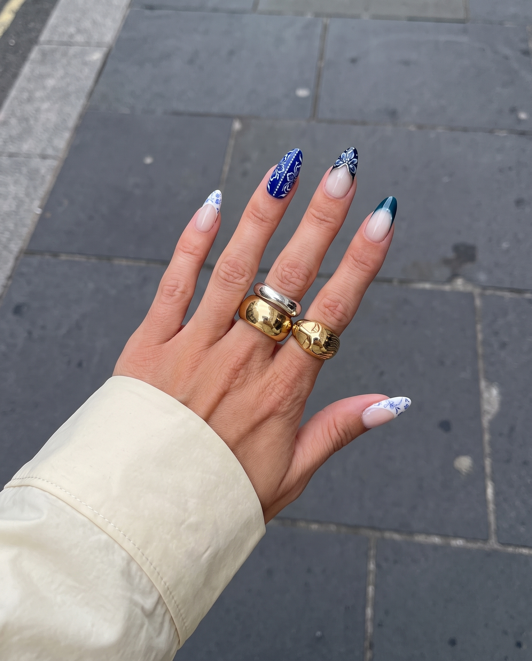 A set of blue and white porcelain-style press-on nails featuring floral patterns, marble designs, and silver accents.