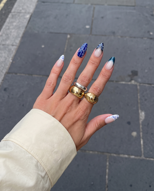 A set of blue and white porcelain-style press-on nails featuring floral patterns, marble designs, and silver accents.