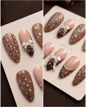 Brown and nude speckled press-on nails with raised white bow embellishments