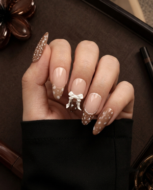 Brown and nude speckled press-on nails with raised white bow embellishments