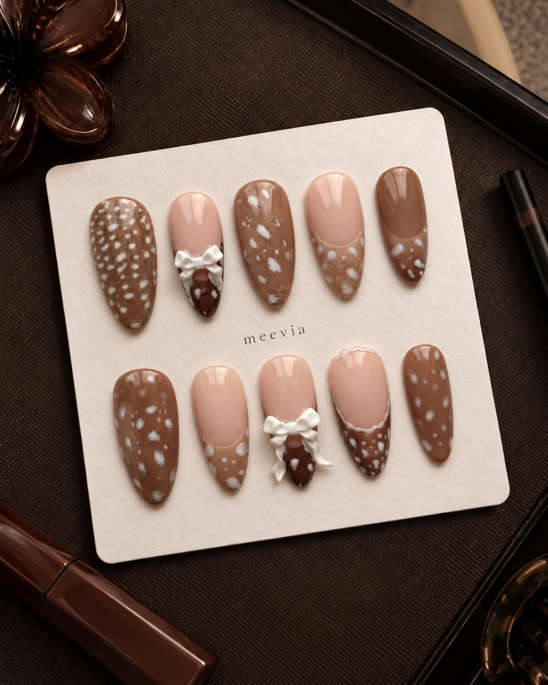 Brown and nude speckled press-on nails with raised white bow embellishments
