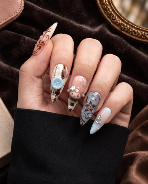 Brown plaid press-on nails with monkey charms, floral details, blue buttons, and rhinestone accents