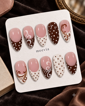 Brown and pink press-on nails with polka dots, French tips, and swirl designs