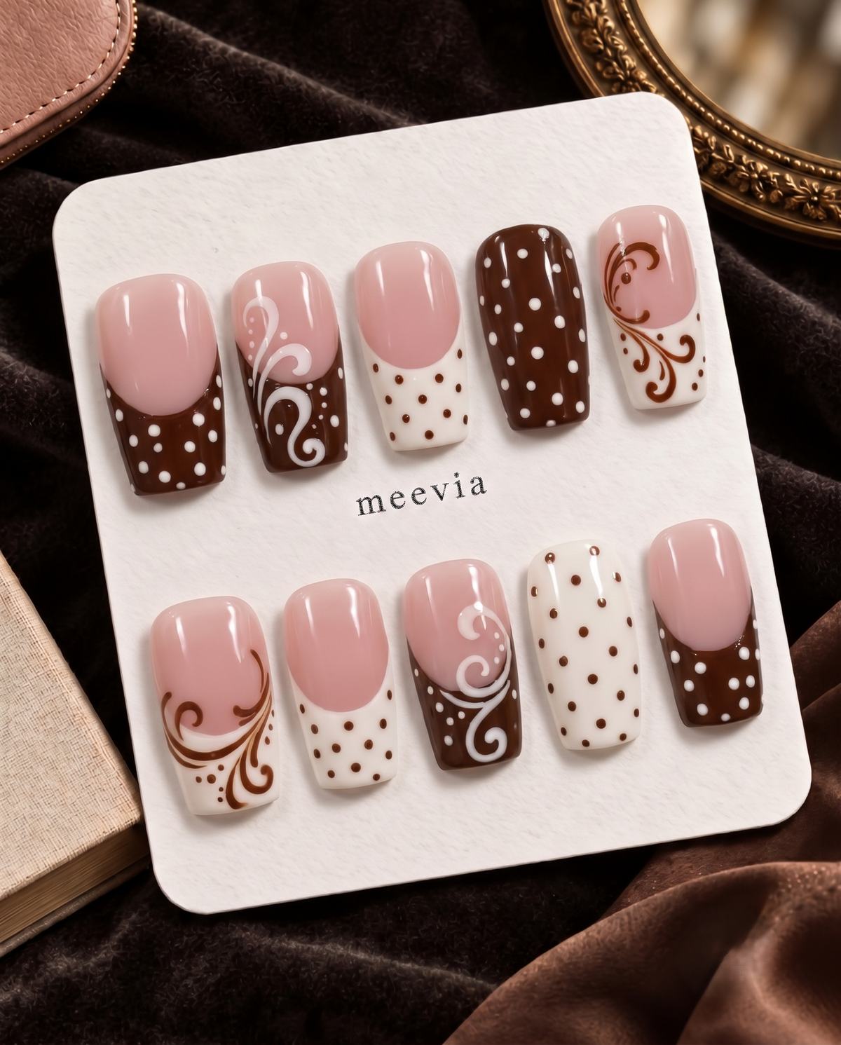 Brown and pink press-on nails with polka dots, French tips, and swirl designs