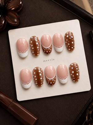 Brown and nude pink press-on nails with white polka dots, French tips, and scalloped accents
