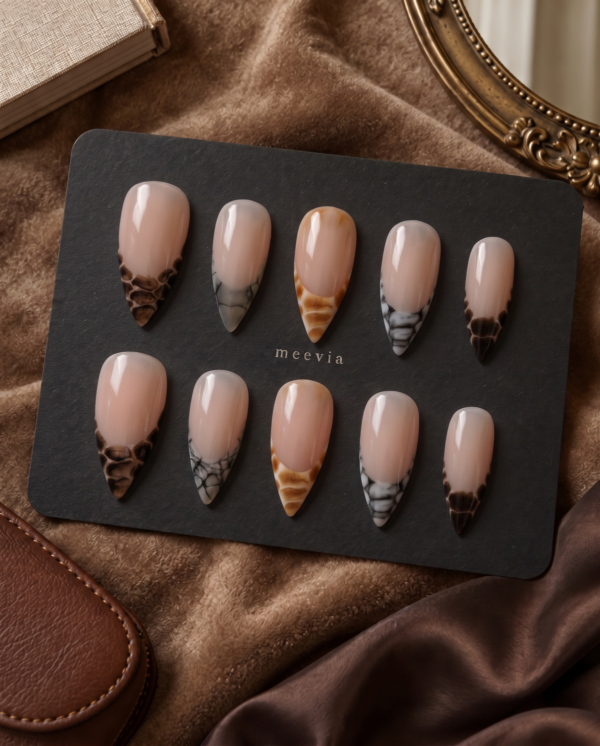 Sheer nude press-on nails with glossy brown, amber, and black snake-print French tips