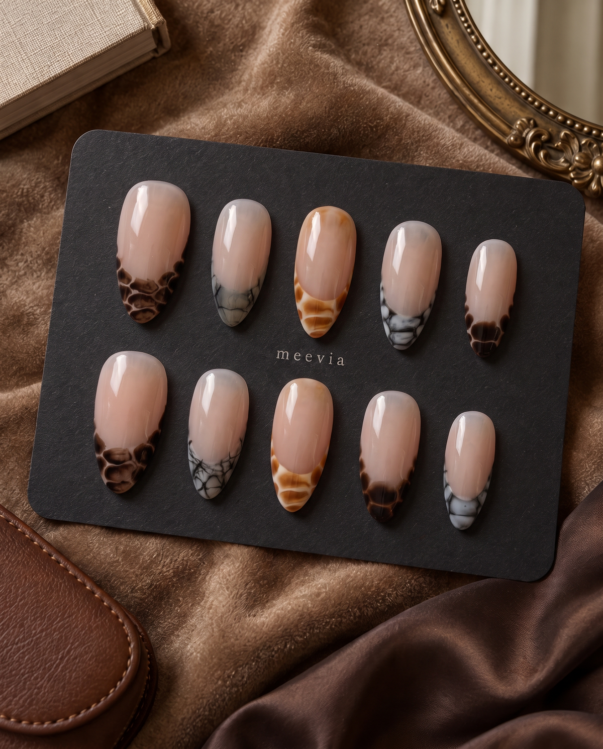 Sheer nude press-on nails with glossy brown, amber, and black snake-print French tips