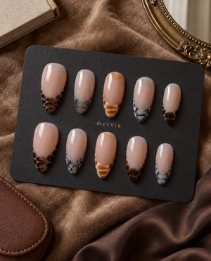 Sheer nude press-on nails with glossy brown, amber, and black snake-print French tips