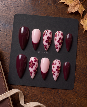 Burgundy floral French tip press-on nails with gold bead accents on a soft pink base