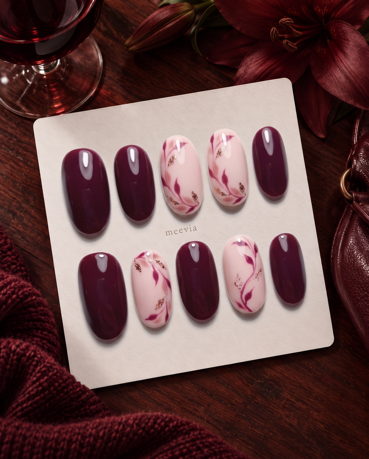 Burgundy and pink floral press-on nails with glossy finish and gold glitter accents