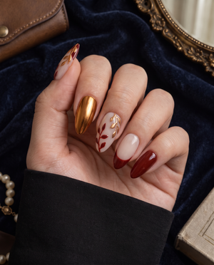Burgundy and gold leaf floral press-on nails with nude bases and a burgundy French tip