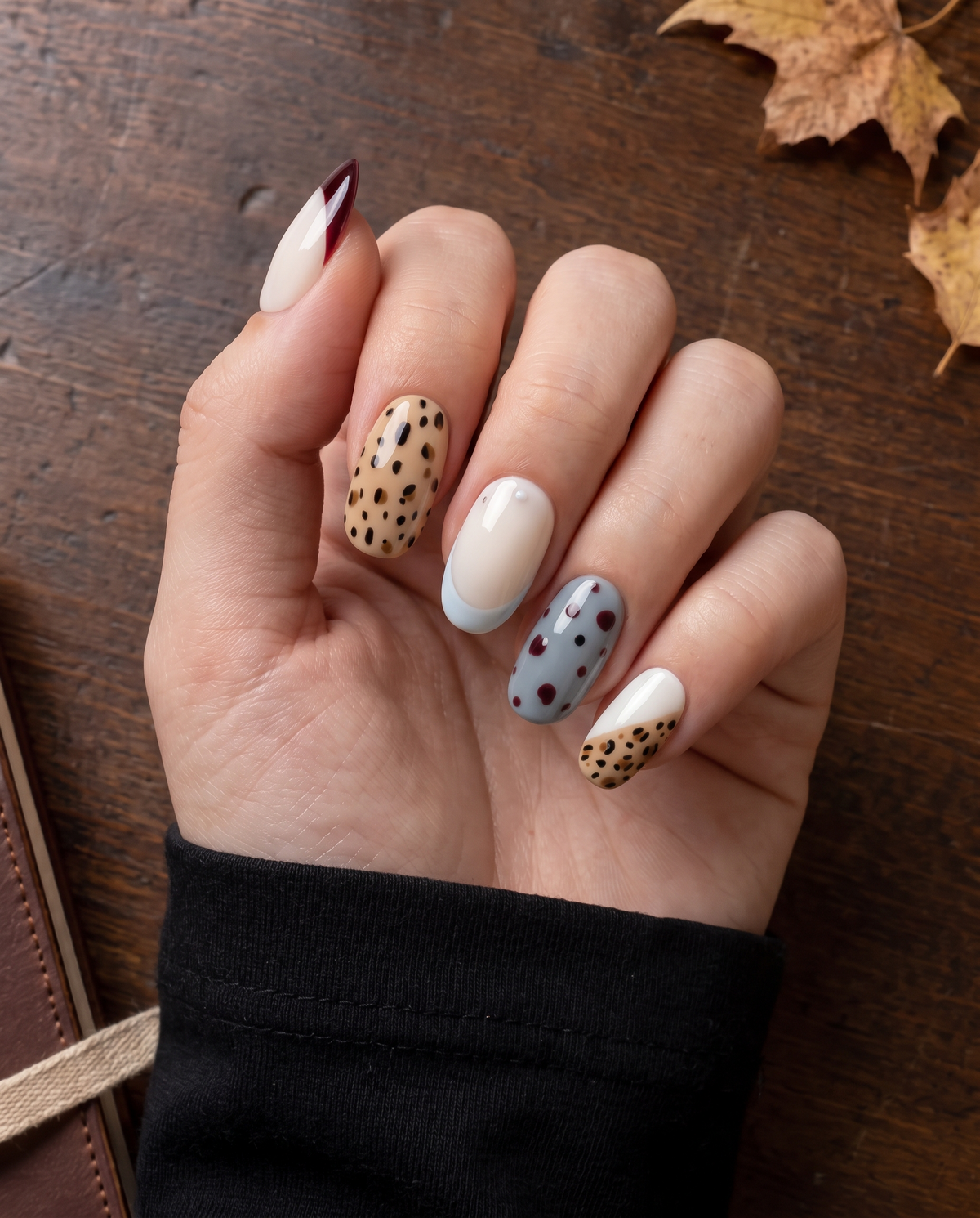 Glossy press-on nails with burgundy French tips, tan leopard print, creamy white bases, and blue dotted accents