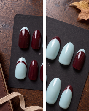 Burgundy and light blue glossy French tip press-on nails arranged on a black display board