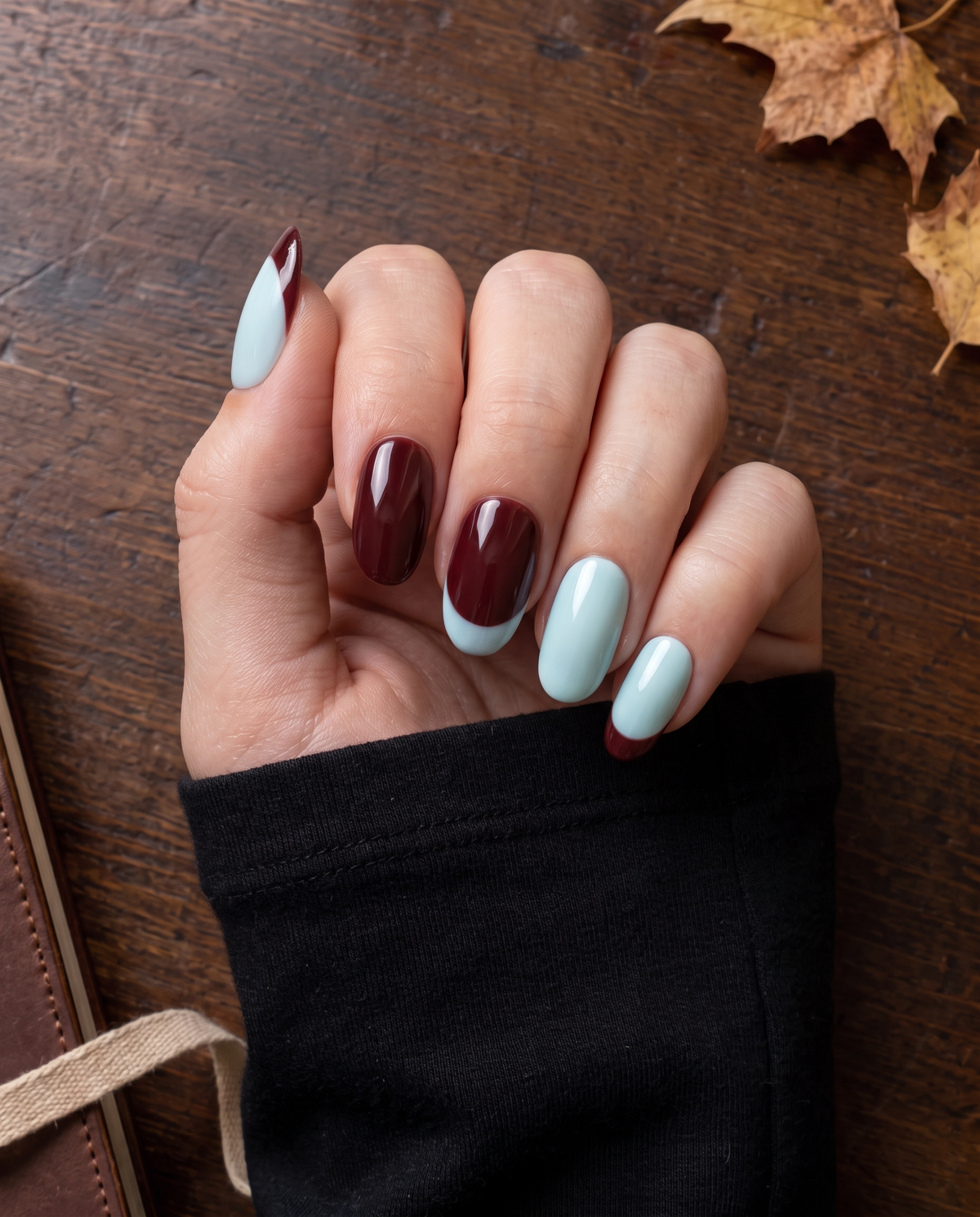 Burgundy and light blue glossy French tip press-on nails arranged on a black display board