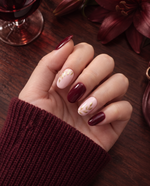 Burgundy and pink press-on nails with glossy finish and gold leaf vine details