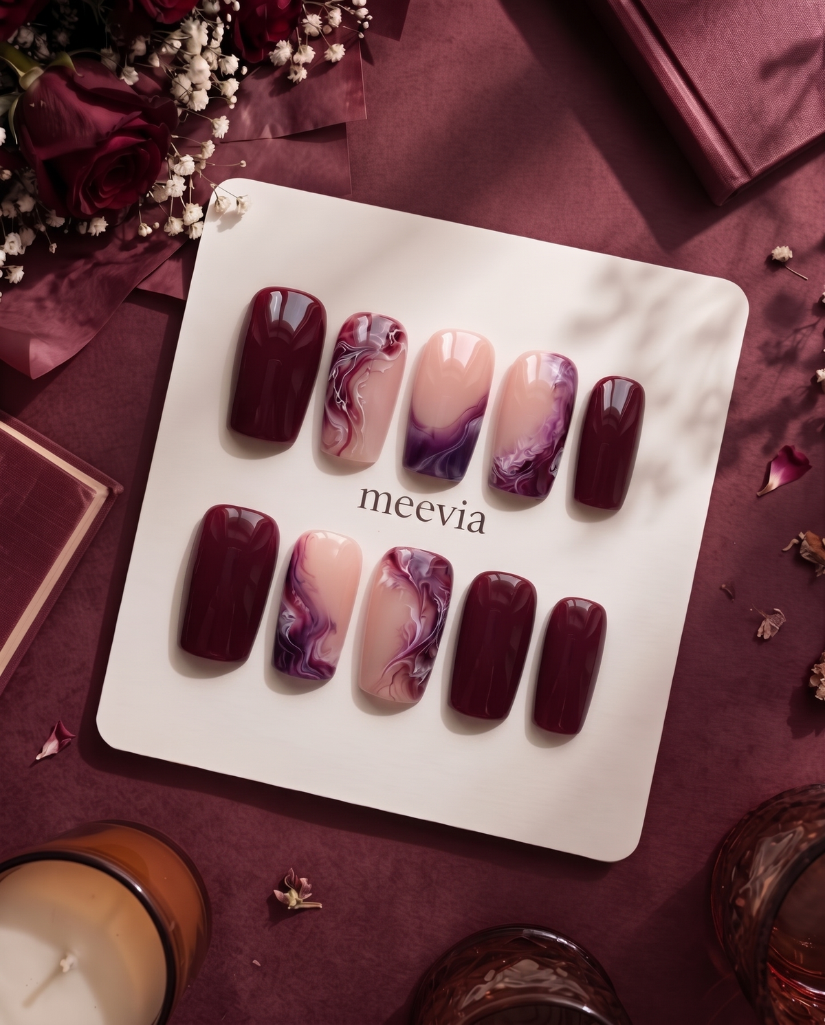 Burgundy and pink glossy marble press-on nails displayed on a white card