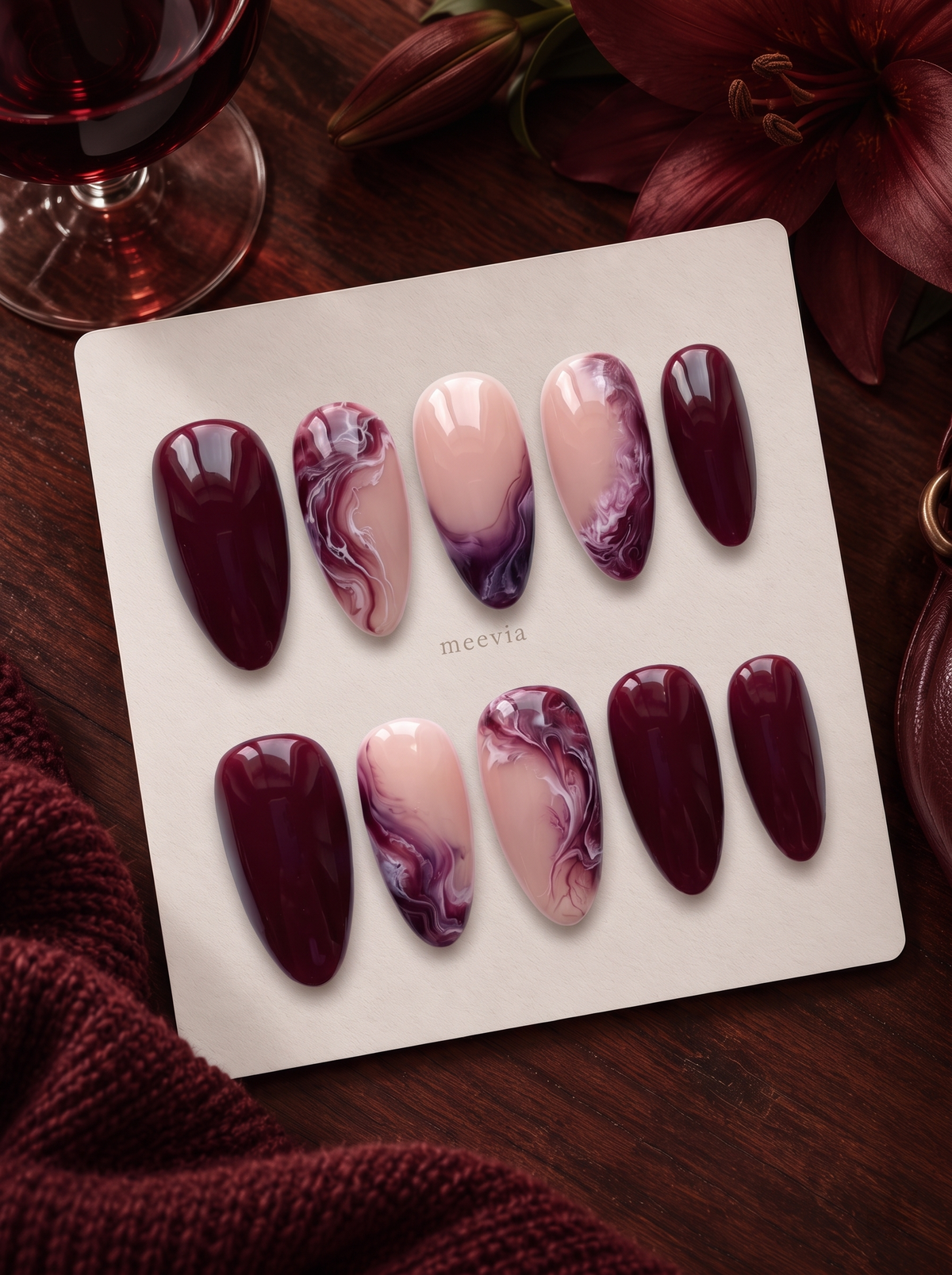 Burgundy and pink glossy marble press-on nails displayed on a white card