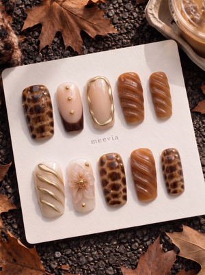 Caramel and brown tortoiseshell floral press-on nails with glossy swirls and gold accents