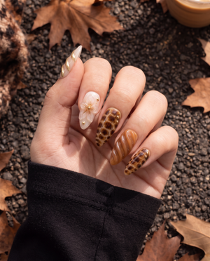 Caramel and brown tortoiseshell floral press-on nails with glossy swirls and gold accents