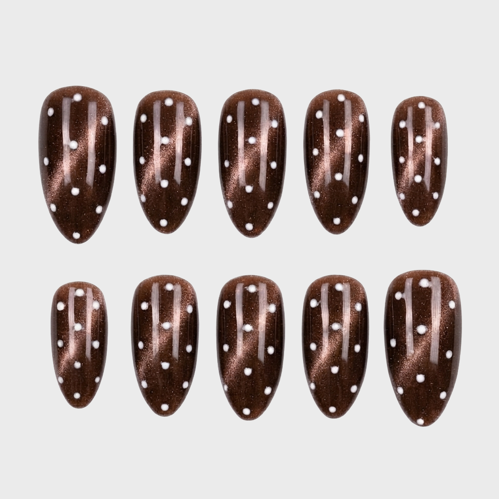 Almond shaped brown cat eye press-on nails with a white polka dot pattern.