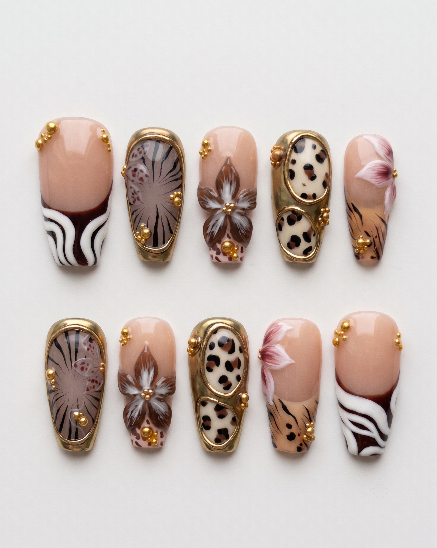 A set of safari-themed press-on nails featuring leopard print, zebra stripes, metallic gold borders, and gold bead embellishments.