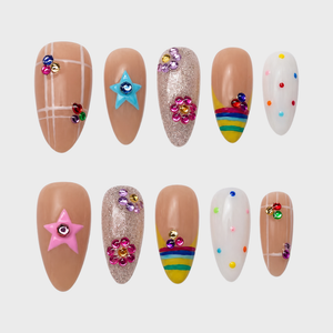 A set of press-on nails featuring nude bases with grid patterns, rainbow tips, glitter, and colorful 3D star and flower charms.