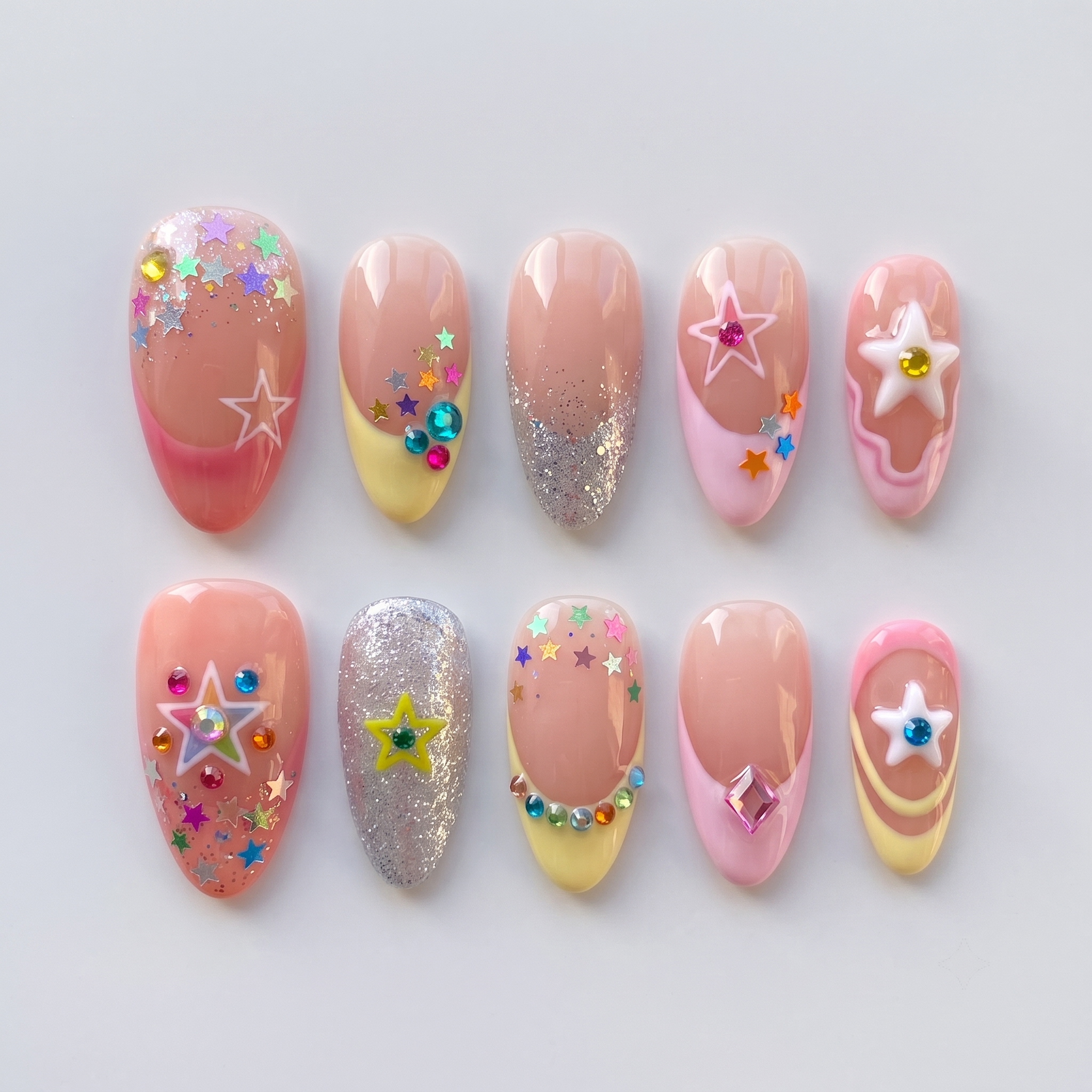 A set of pastel press-on nails featuring colorful star charms, rhinestone accents, and glitter French tips.