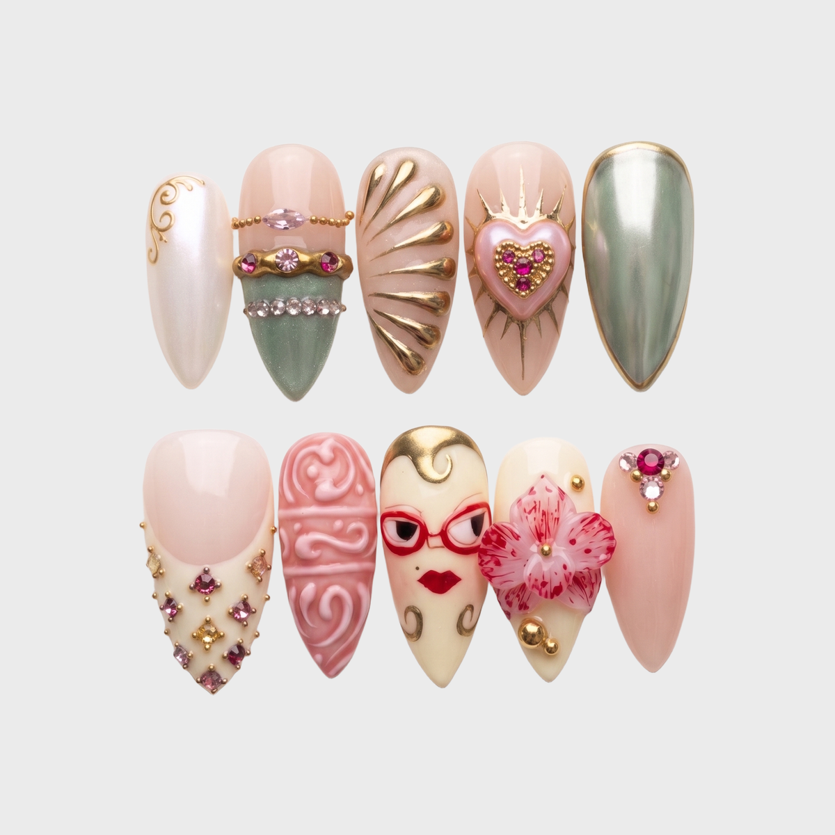 A set of eclectic press-on nails in pink, gold, and green featuring a 3D flower, face illustration, and rhinestone details.