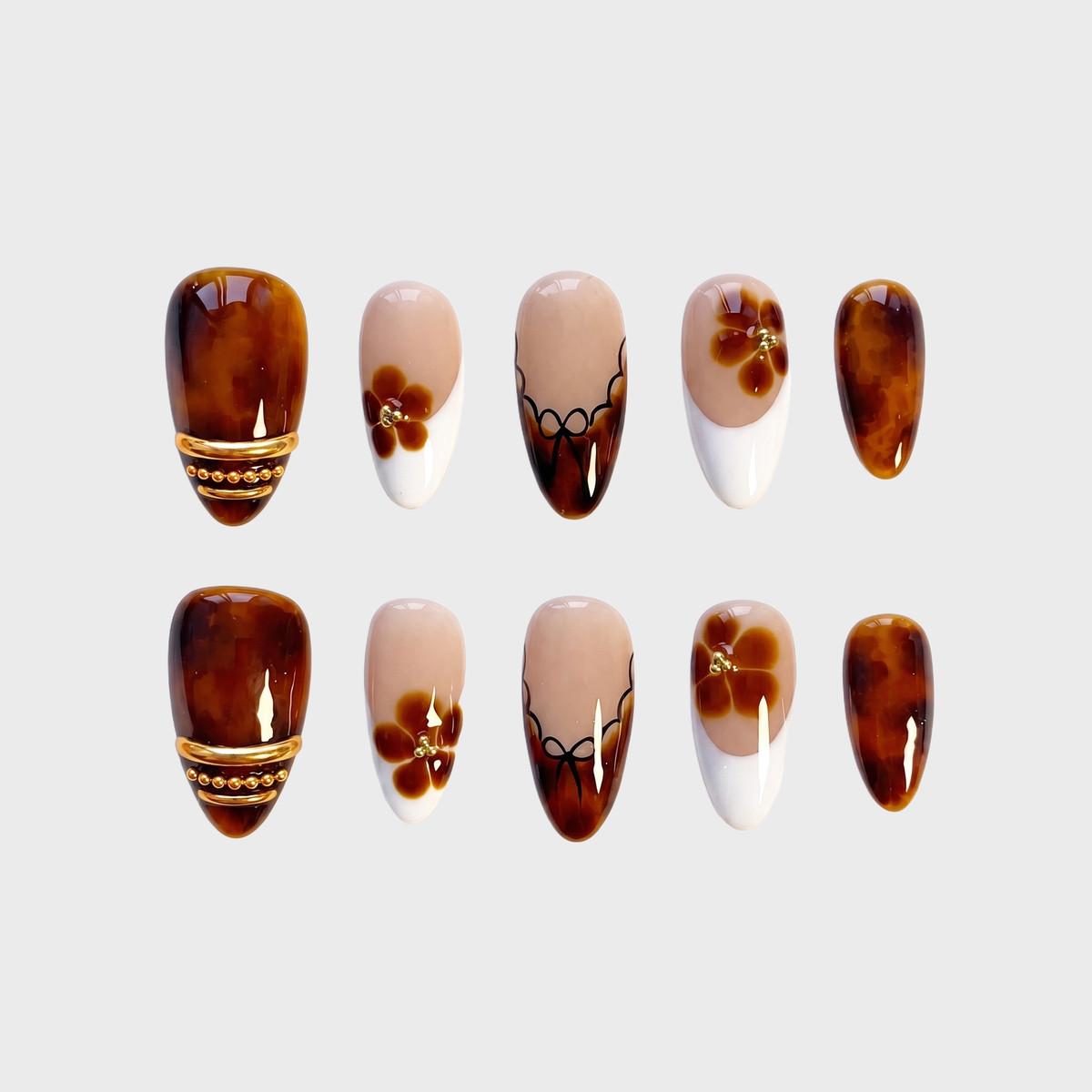 A collection of press-on nails featuring tortoiseshell patterns, floral motifs, and gold embellishments.