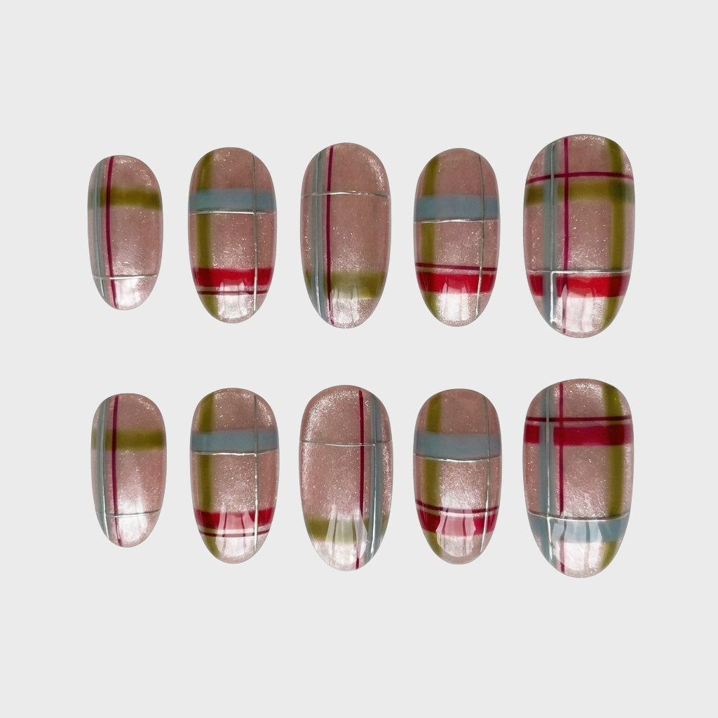 A set of press-on nails with a shimmery nude base and a red, olive, and blue plaid pattern with silver line accents.