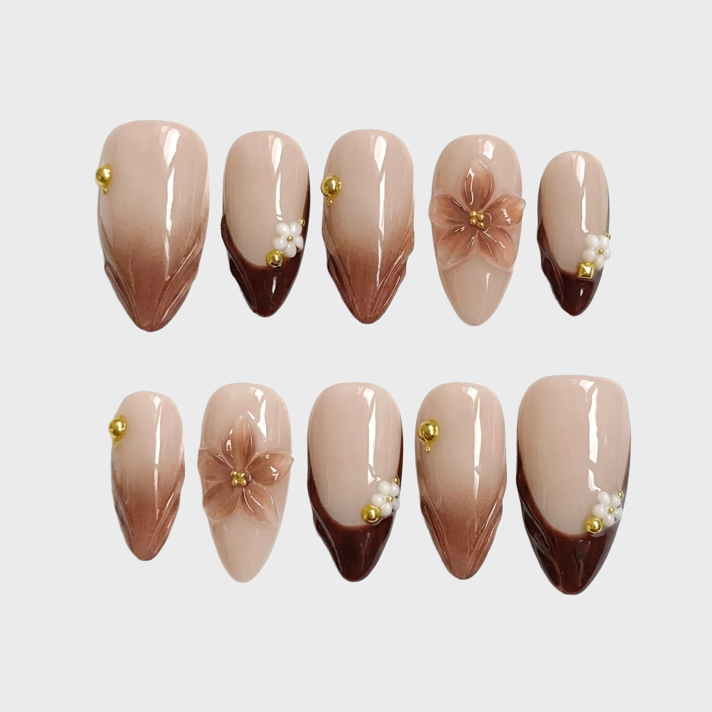Brown ombre french tip press-on nails with 3D floral accents and gold beads.
