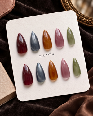 Glossy almond press-on nails in translucent burgundy, slate blue, amber, mauve, and olive green tones