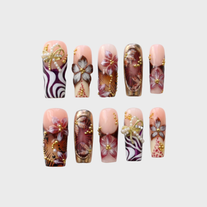 Set of almond-shaped press-on nails featuring pink and white colors, gold leopard print patterns, raised bows, and rhinestone embellishments.