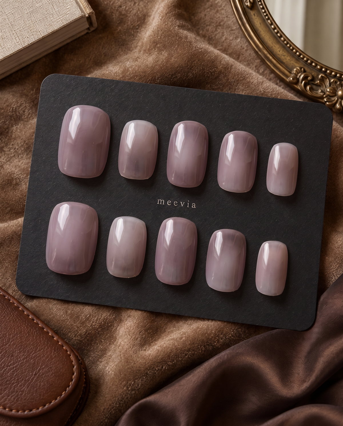 Glossy mauve taupe almond press-on nails displayed on a black nail card