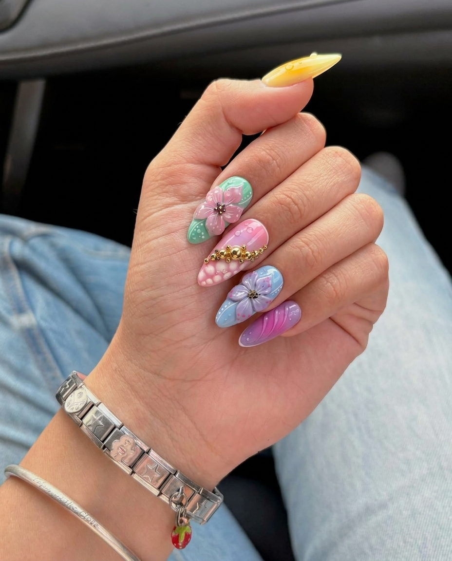 A collection of colorful press-on nails featuring 3D floral designs, water droplets, and gold bead embellishments.
